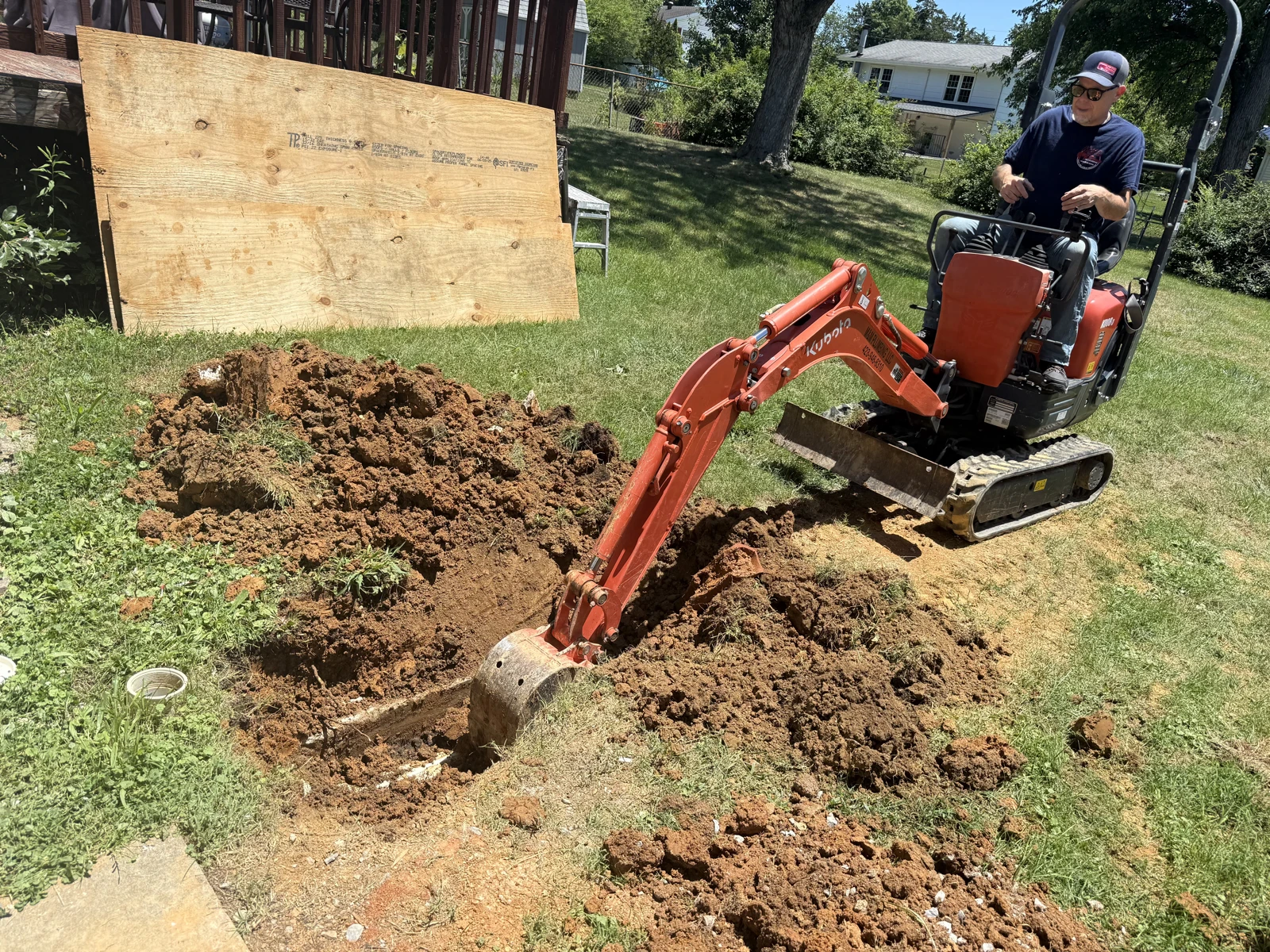 M&M Plumbing operating a compact excavator for underground pipe work at a residential property