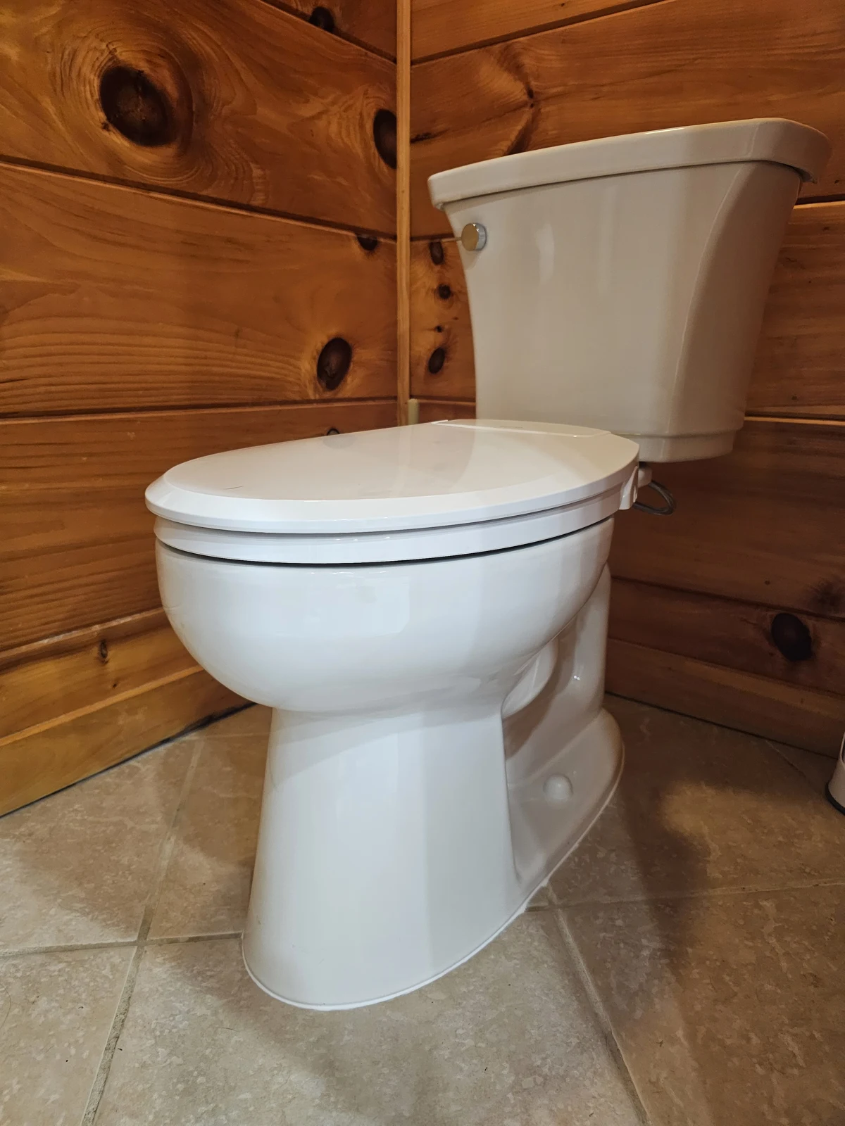 Replacement toilet installed in a wood-paneled bathroom